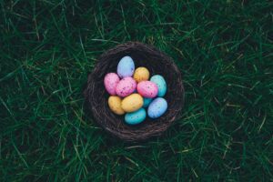 Colored Easter eggs in brown basket in grass