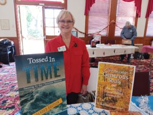 Betsy Schwarzentraub setting up her book table with 2 book posters at Gold Country Writers in Auburn, Dec. 2024.