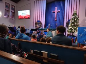 Woman in worship reading a story to the children the Sunday after Christmas Day